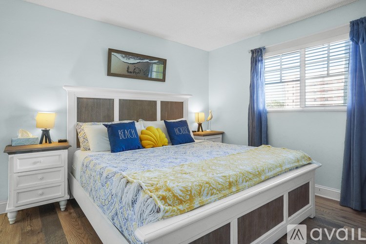 A bedroom with a bed, nightstands, and a window.