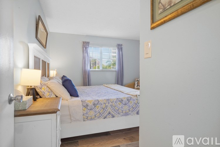 A bedroom with a bed, nightstand, and a painting on the wall.