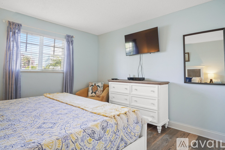 A bedroom with a bed, dresser, mirror, and window with curtains.