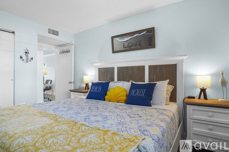 A bedroom with a bed, nightstand, and a framed picture on the wall.