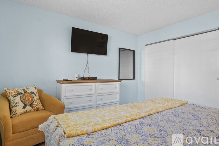 A bedroom with a bed, a chair, and a TV mounted on the wall.