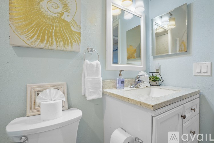A bathroom with a white toilet, a white sink, and a yellow and white artwork on the wall.