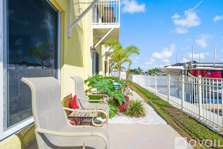 A patio with a chair and a table with a basket of fruit on it.