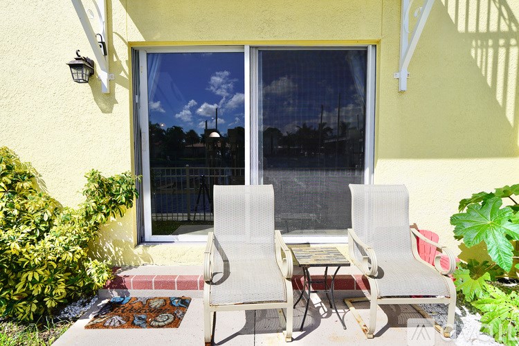 Two white chairs are placed on a patio.