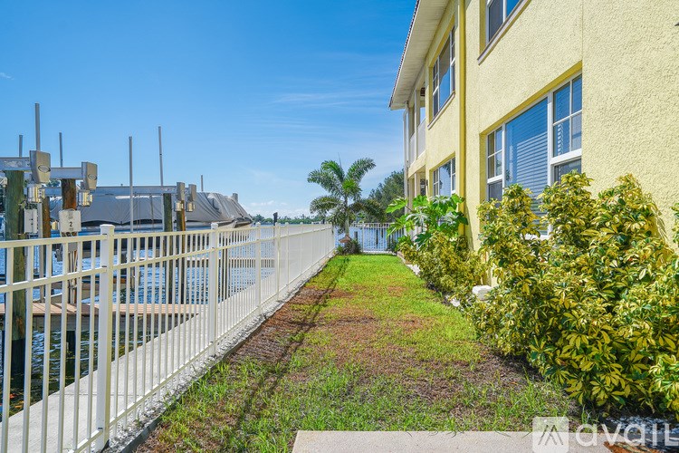 A yellow building with a white fence and green plants in front.
