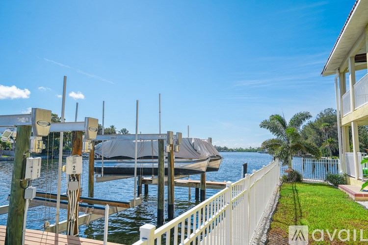 A boat is docked at a pier with a house and lawn in the foreground.