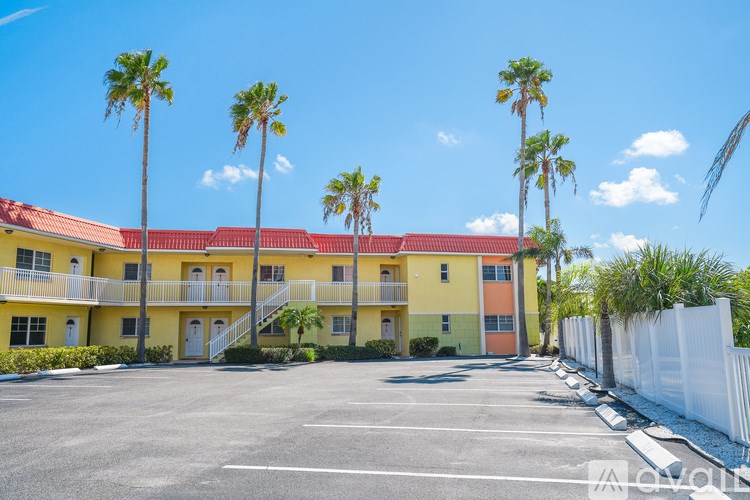A sunny day at a yellow building with palm trees.