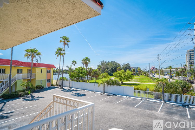 A parking lot with a white fence and palm trees in the background.