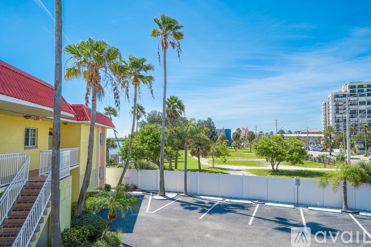 A yellow building with a red roof is surrounded by palm trees.