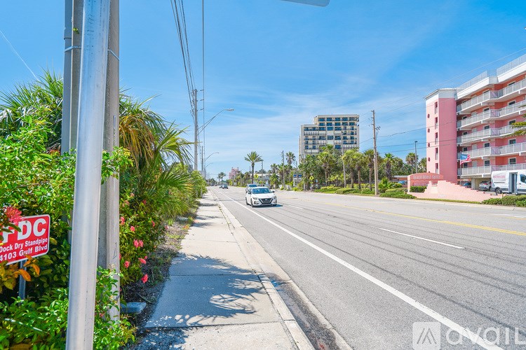 A street view with a car driving on the road and buildings on the side.