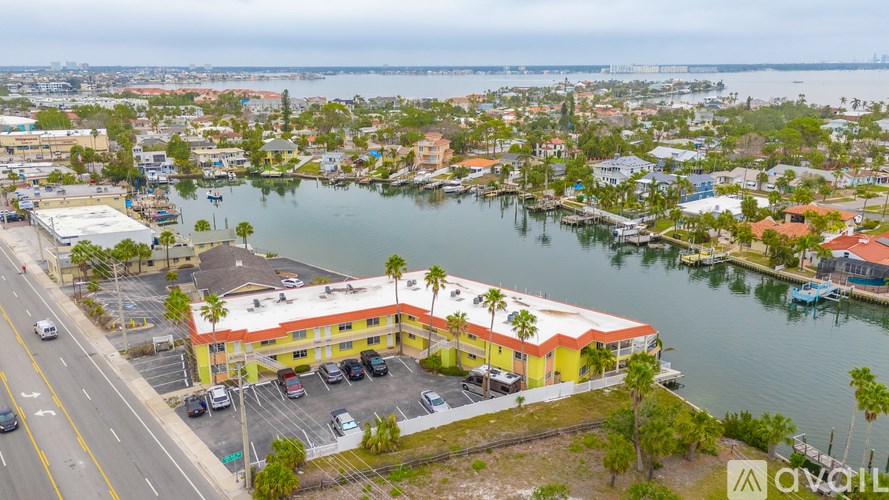 A yellow building with a red roof is in the foreground of a waterfront city scene.