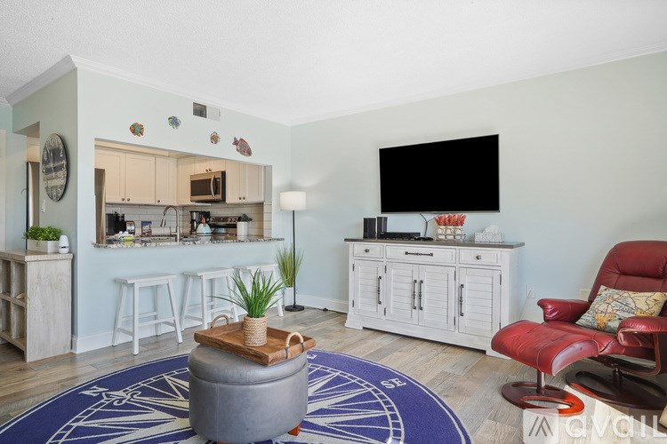 A living room with a grey ottoman and a red chair.
