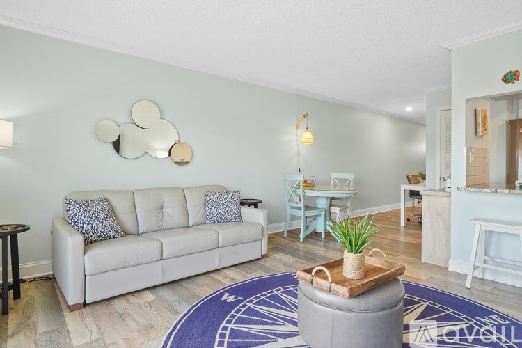 A living room with a white couch and a round rug.
