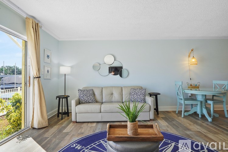 A living room with a white couch and a blue rug.