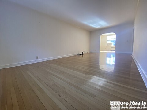 A room with wooden flooring and white walls.