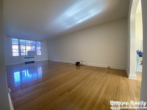 A room with wooden flooring and a window letting in natural light.