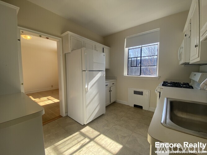 A kitchen with white appliances and a window.