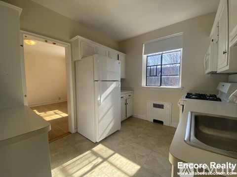 A kitchen with white appliances and a window.