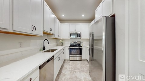 A kitchen with white cabinets and appliances.