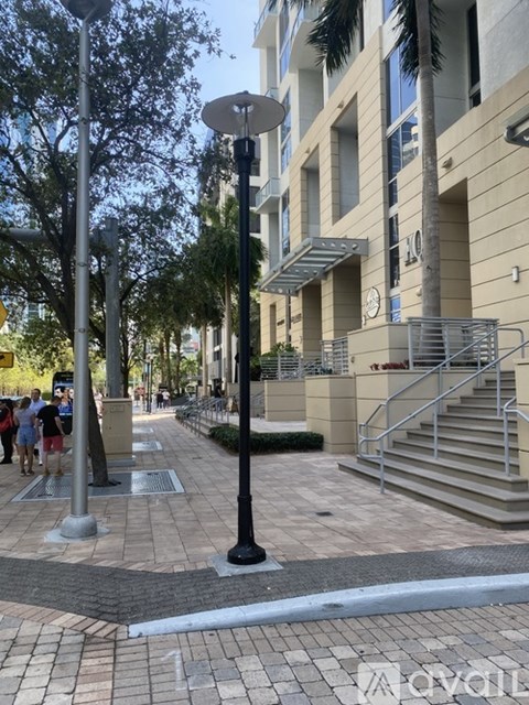 A street view with a building, a tree, and a few people.