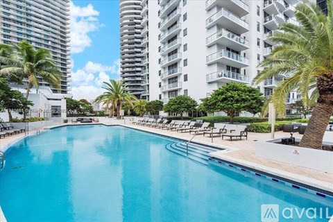 A large swimming pool surrounded by palm trees and lounge chairs.