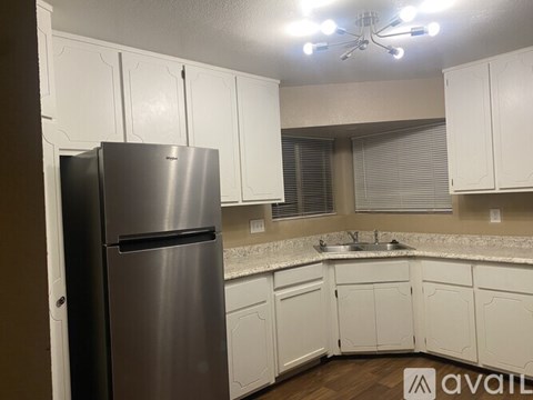 A kitchen with a stainless steel refrigerator and white cabinets.