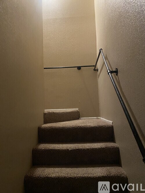 A staircase with a metal handrail and carpeted steps.