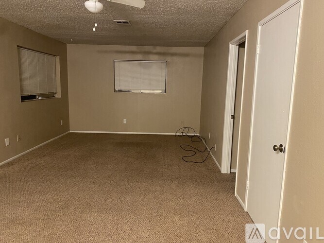 A room with a carpeted floor, a ceiling fan, and a window with blinds.
