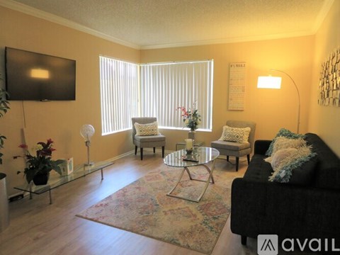 A living room with a couch, chairs, and a television.