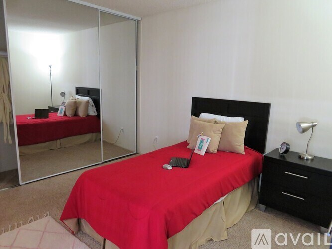 A bedroom with a red bedspread and a black headboard.
