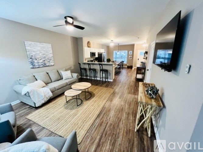 A living room with a white sofa, a wooden coffee table, and a television mounted on the wall.