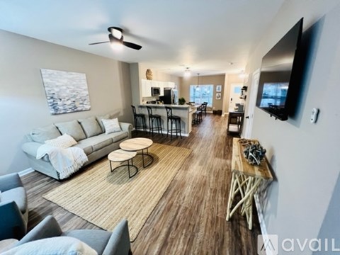 A living room with a white sofa, a wooden coffee table, and a television mounted on the wall.