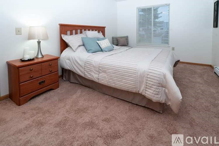 A bedroom with a bed, nightstand, and carpet.