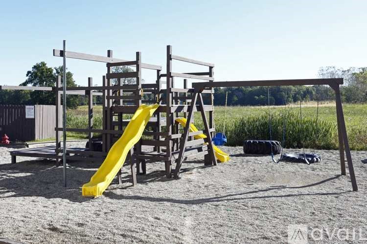 A playground with a yellow slide and a wooden structure.
