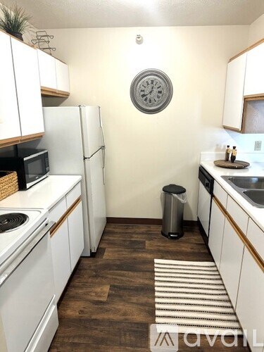 A kitchen with white cabinets and a clock on the wall.