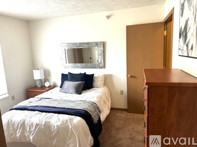 A bedroom with a bed, nightstand, and a mirror on the wall.