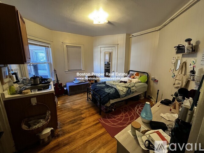 A cluttered room with a bed, a table, and a window.