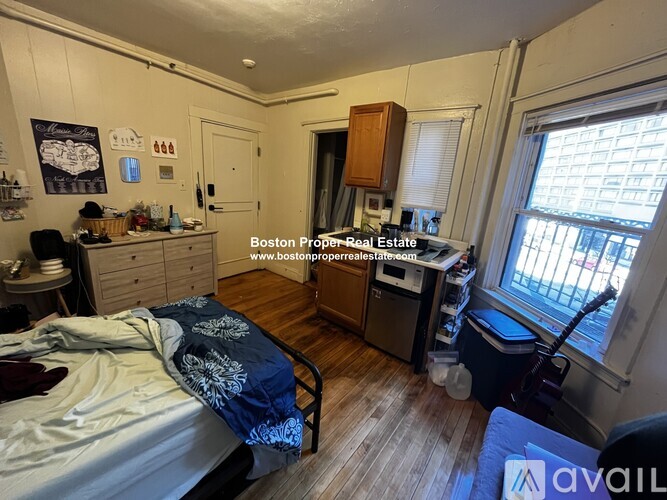 A bedroom with a bed, a desk, and a window.