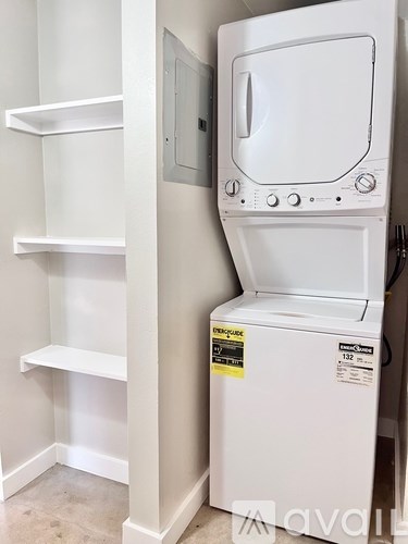 A white dishwasher is in a kitchen with white shelves.