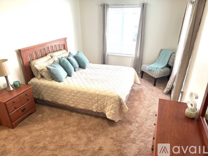 A bedroom with a large bed, a chair, and a nightstand.