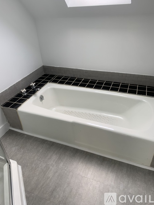A white bathtub with a silver faucet is in a bathroom with a grey floor and white walls.