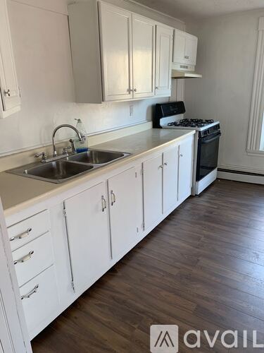 A kitchen with white cabinets and a stove top oven.
