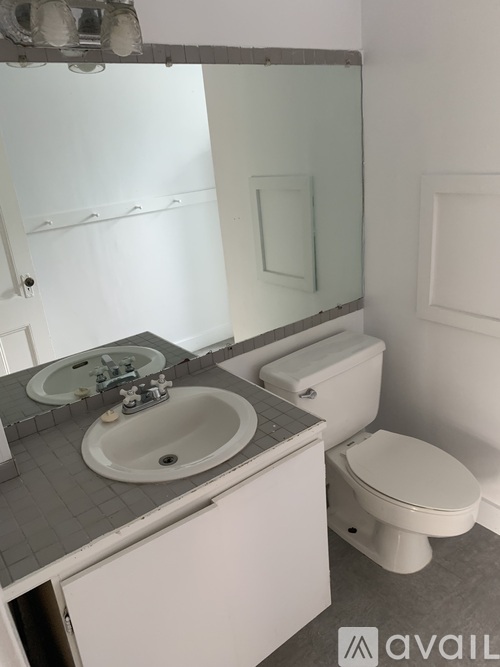 A bathroom with a toilet, sink and mirror.