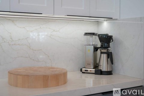 A kitchen counter with a coffee maker and a wooden chopping board.