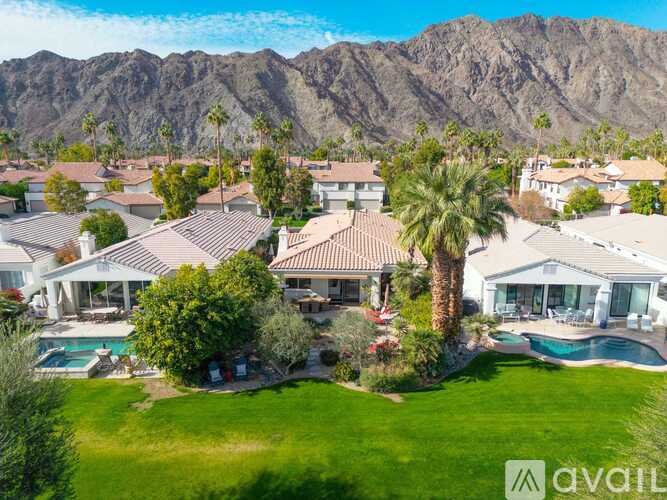A large house with a pool in front of a mountain.