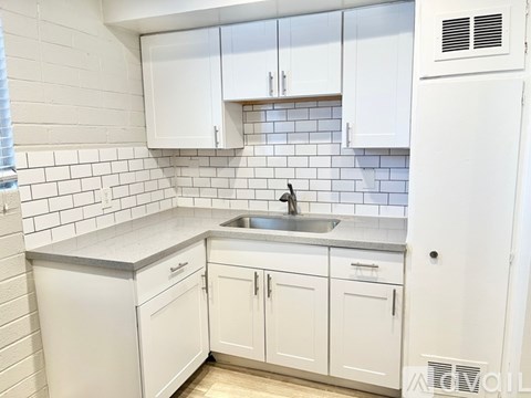 A kitchen with white cabinets and a white refrigerator.