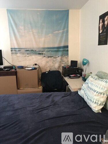 A room with a bed, a desk with a computer, and a poster on the wall.