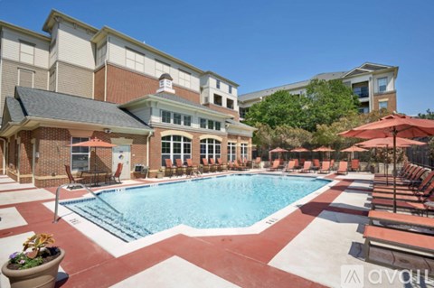 A large outdoor swimming pool surrounded by lounge chairs and umbrellas.