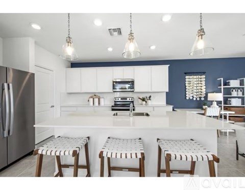 A modern kitchen with white cabinets and a large island with four stools.
