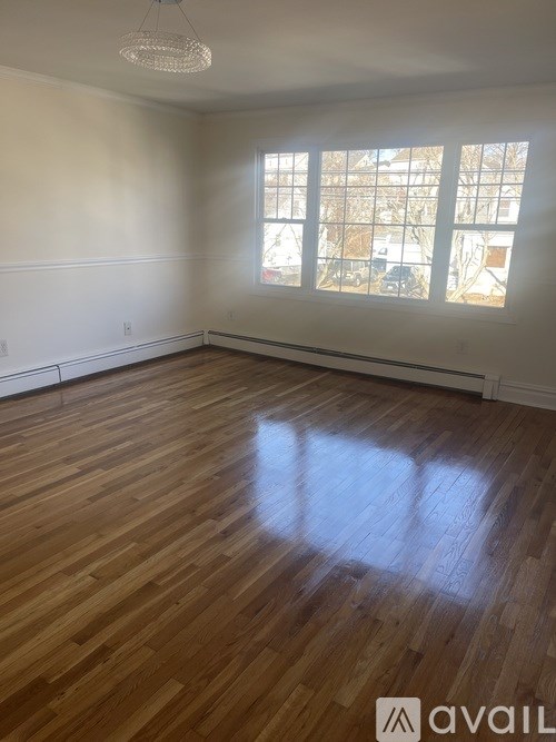 A room with wooden flooring and a window letting in sunlight.